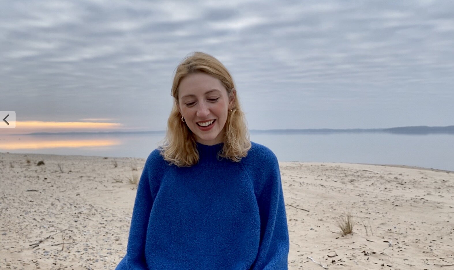 Abby smiling on a beach at sunset